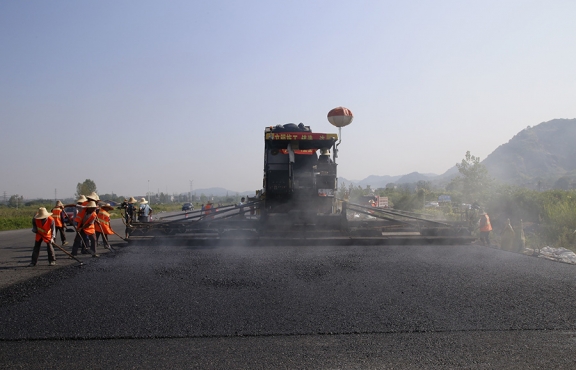 2019年8月，宜春經(jīng)開區(qū)S311路面攤鋪現(xiàn)場，工友們輔助路面兩側的分料、補窩等作業(yè)